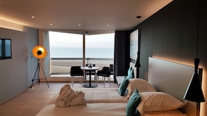 Une chambre d’hôtel avec un lit, un bureau, une chaise et une vue sur la mer.