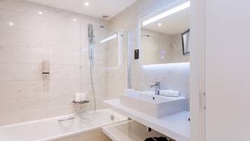 A modern bathroom with a glass-enclosed shower, a white sink, and a large mirror.