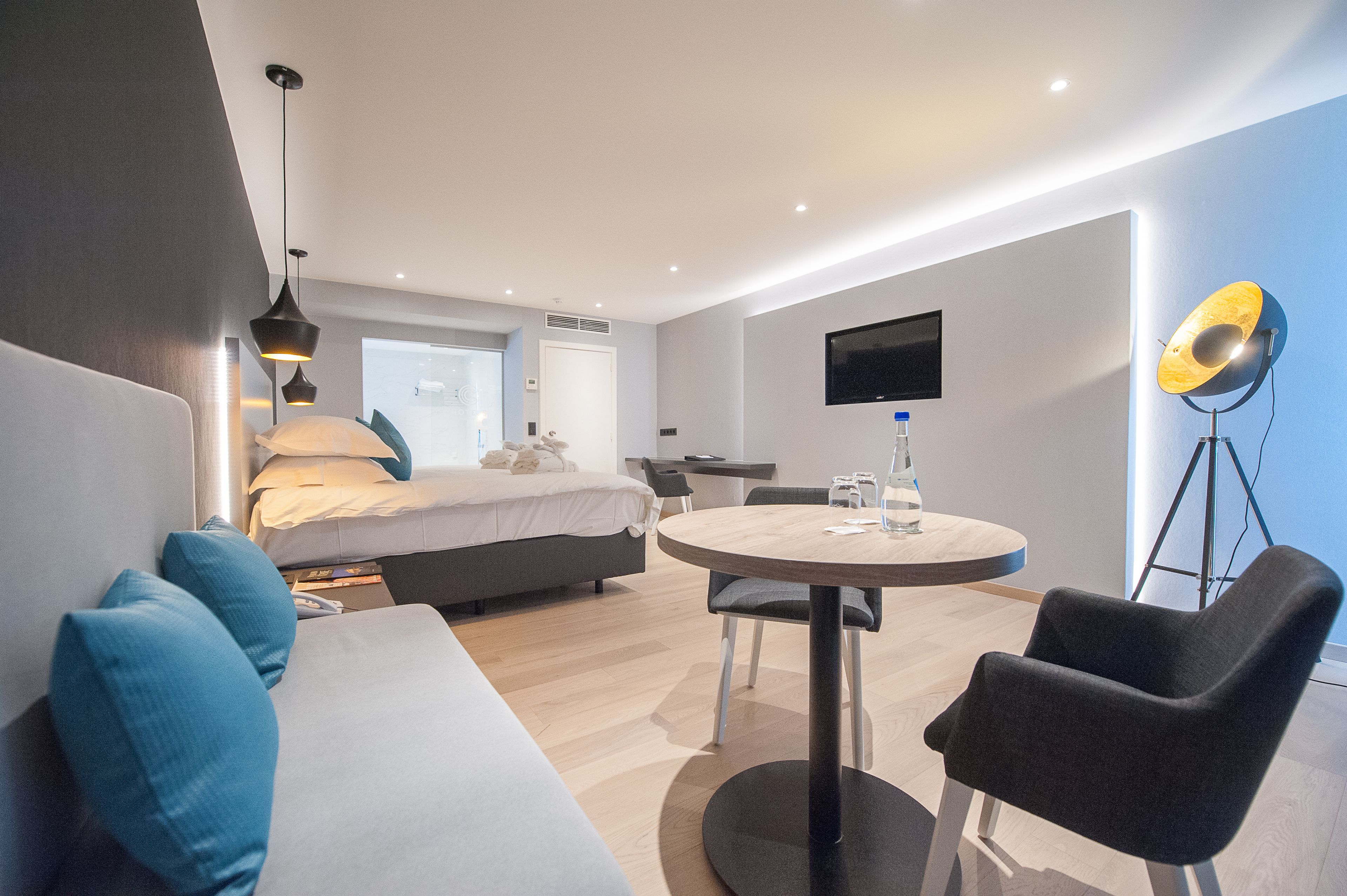 Una habitación de hotel moderna con una cama, un sofá, una mesa redonda y un escritorio.