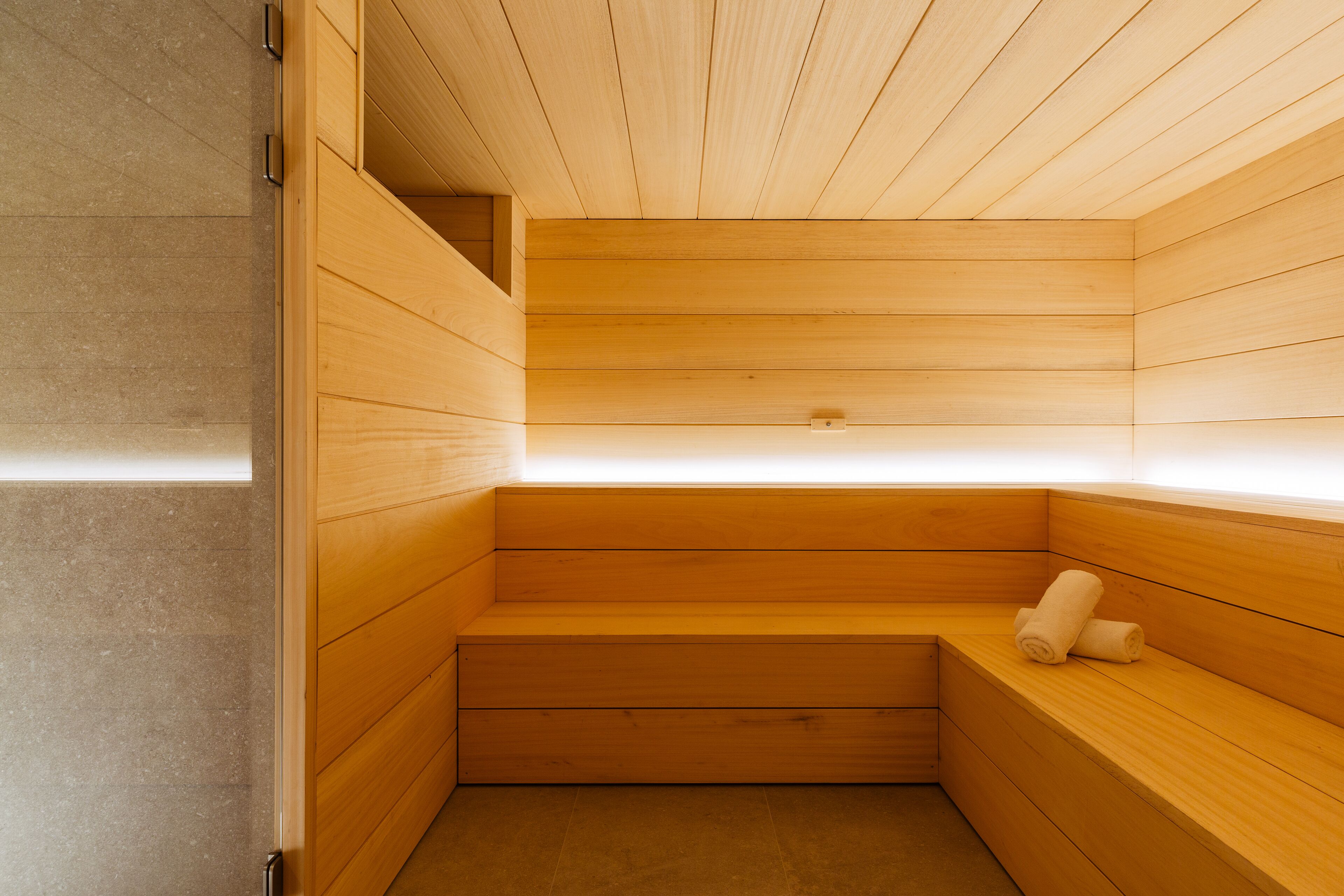 Sauna de fusta amb bancs i una cadira amb tovalloles.
