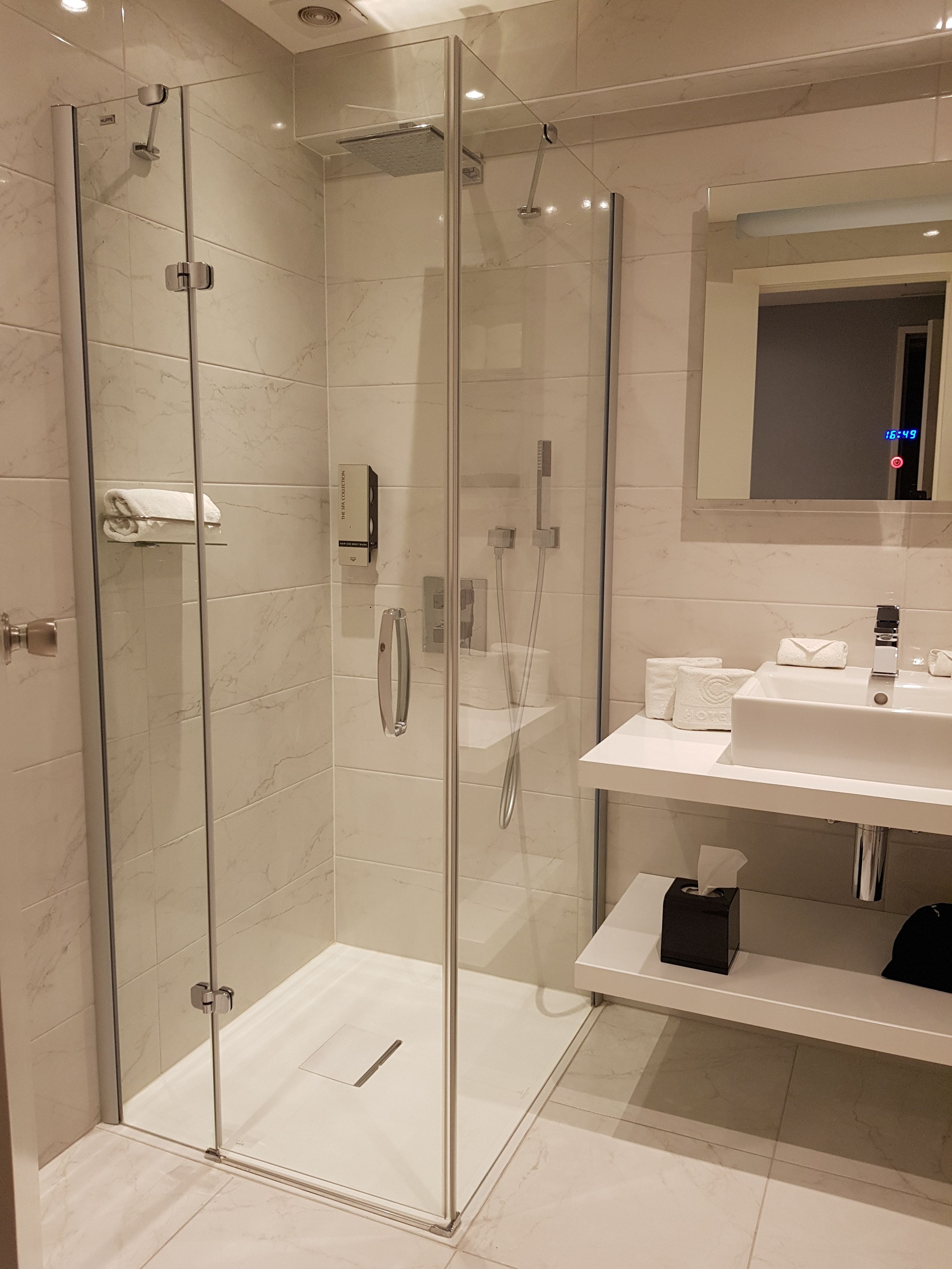 A modern bathroom with a glass-enclosed shower, a white sink, and a mirror above the sink.