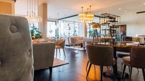 Un hall d’hôtel moderne avec une table ronde, des sièges confortables et une grande fenêtre laissant entrer la lumière naturelle.