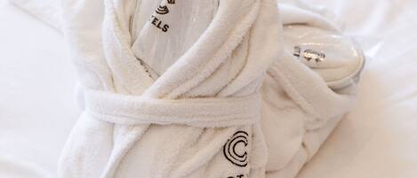 Un albornoz blanco doblado con cuidado con el texto 'HOT ANDRO' y un logotipo sobre una cama.