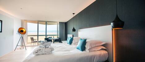 Una habitación de hotel moderna con una cama grande, un escritorio y vistas a la playa.