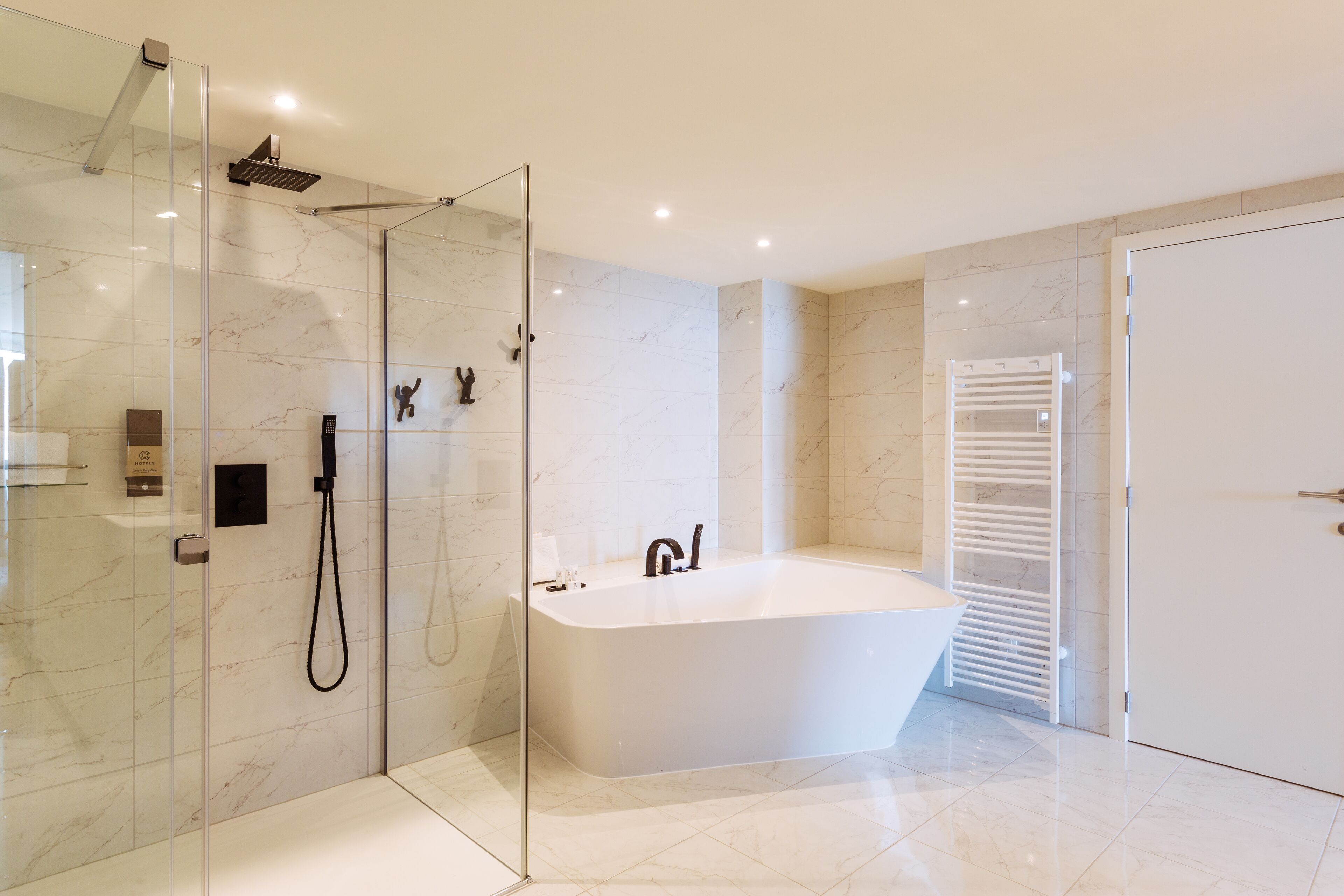 Une salle de bain moderne avec une douche à parois de verre, une baignoire sur pieds et un porte-serviettes blanc.