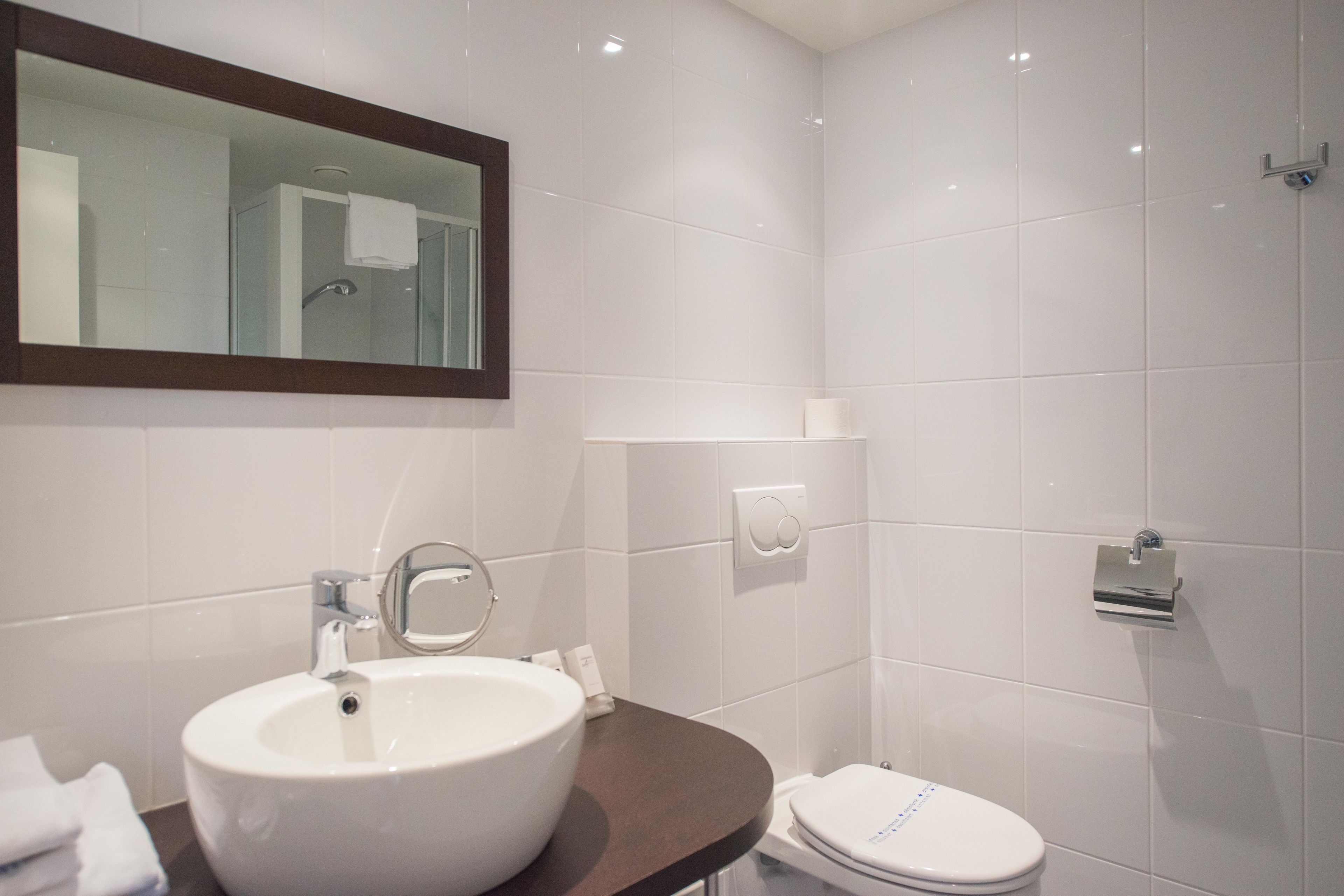 A modern bathroom with a white sink, a toilet, and a glass shower enclosure.
