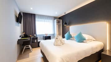 A modern hotel room with a large bed, a desk with a chair, a wardrobe, and a TV mounted on the wall.