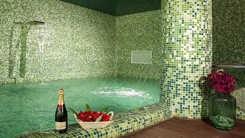 En kakelbeklädd jacuzzi med en flaska champagne och en korg med jordgubbar.