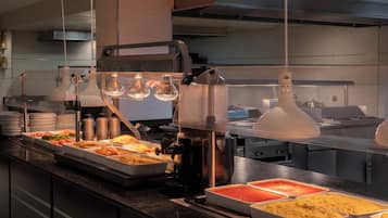 Montaje tipo bufé con diversas opciones de comida y una máquina de café.