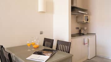 Un coin repas avec une table dressée pour deux personnes, un magazine et deux verres de jus d’orange.
