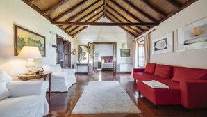 A spacious living area with a wooden ceiling, a red sofa, white armchairs, and a large rug. - Hotel Rural las Calas (Vega de San Mateo)