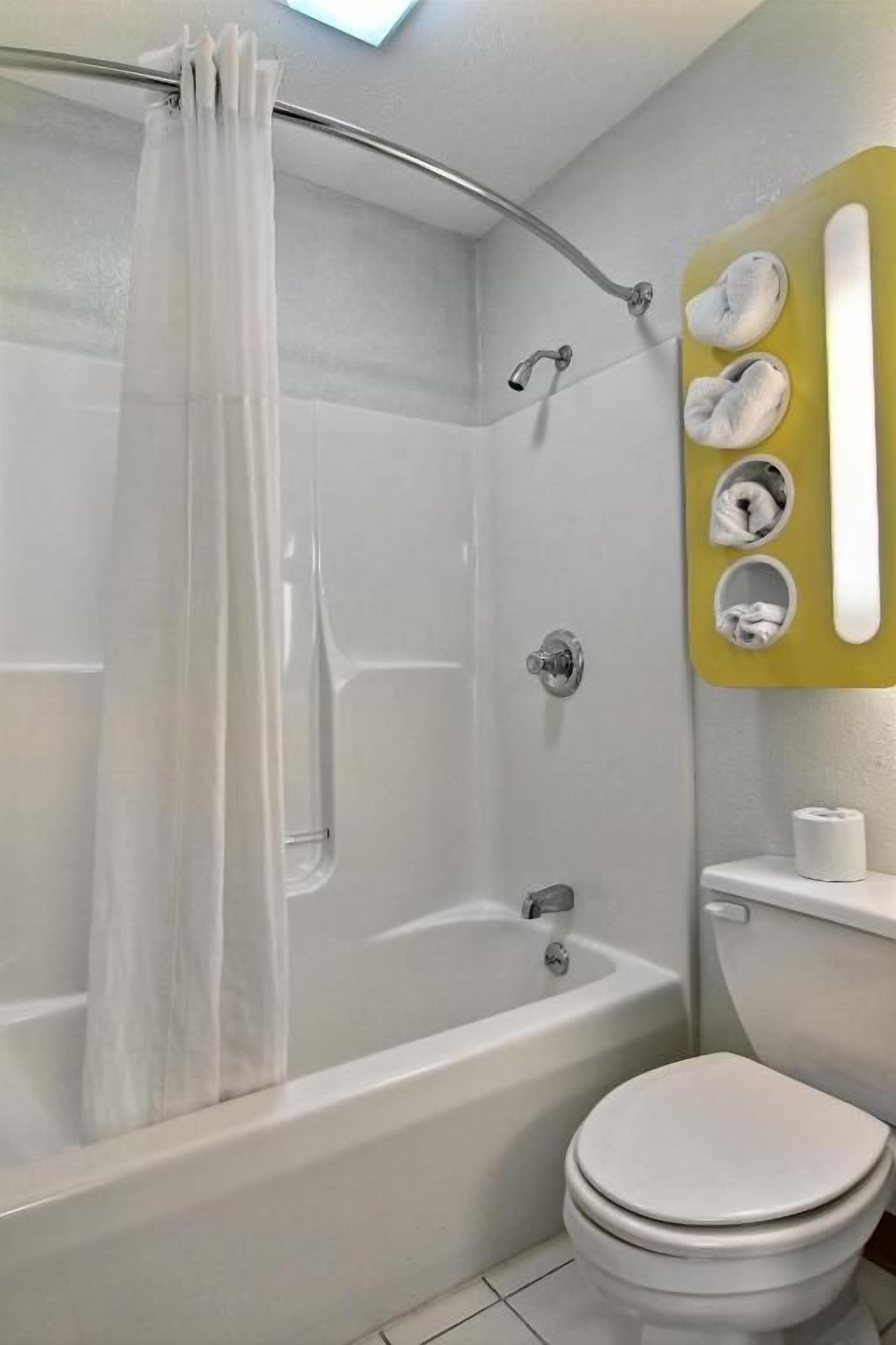 Un baño con bañera, inodoro y cortina de ducha.