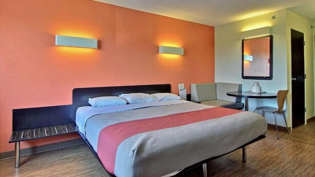 Une chambre d’hôtel équipée d’un lit, d’un bureau, d’une chaise et d’un téléviseur fixé au mur.