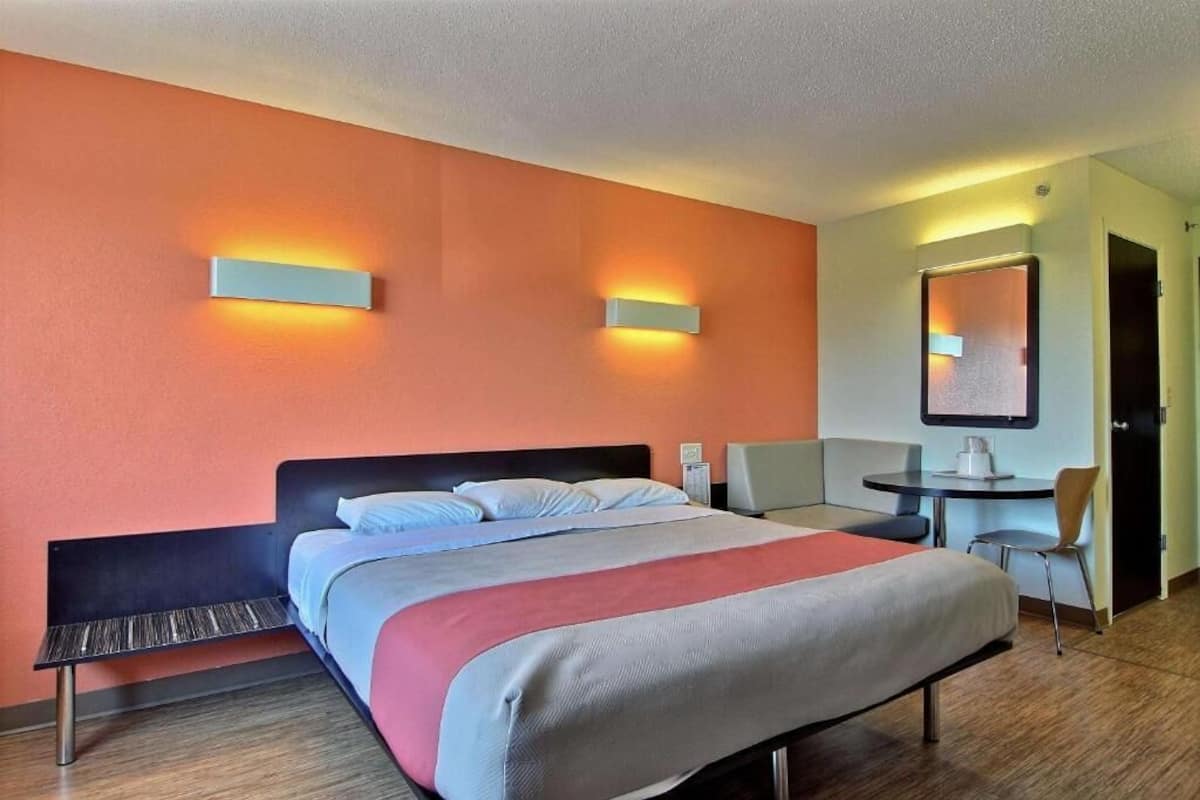 Une chambre d’hôtel équipée d’un lit, d’un bureau, d’une chaise et d’un téléviseur fixé au mur.