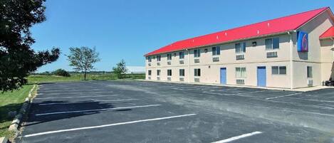 A building with a red roof and a parking lot in front.