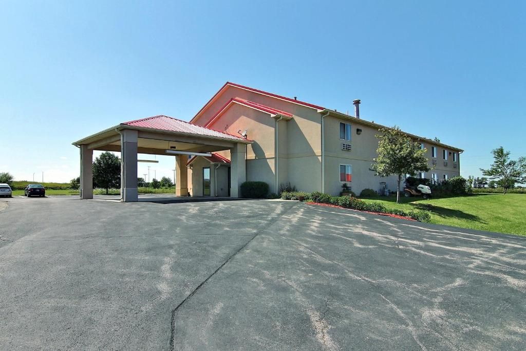 A hotel with a covered parking area, a red roof, and a well-maintained lawn.