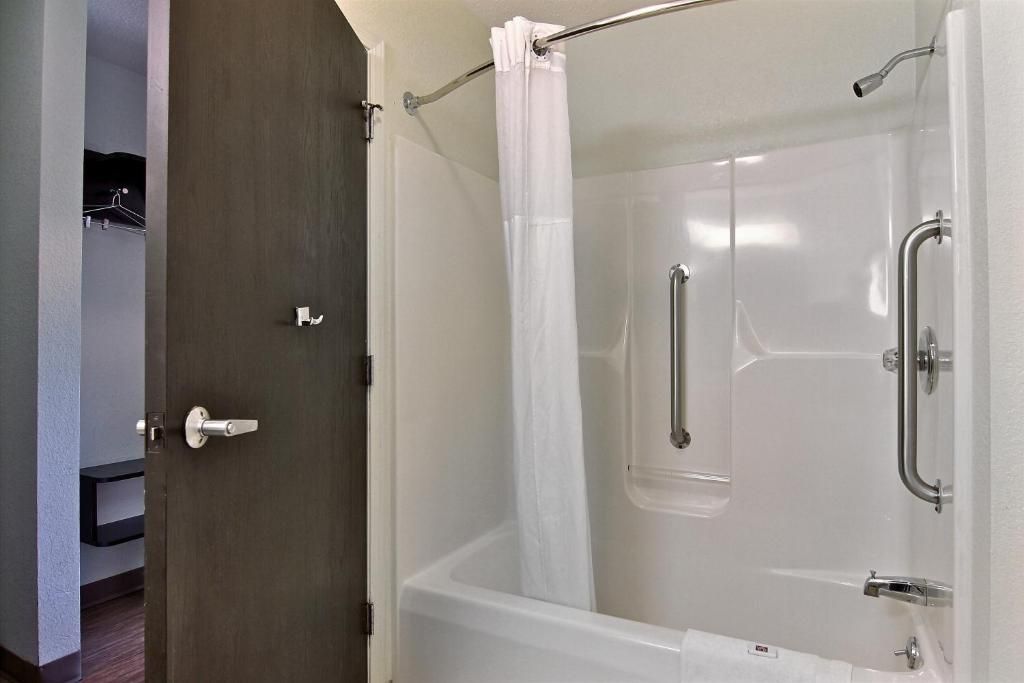 Una ducha a nivel con puerta de vidrio, un cabezal de ducha y una barra de apoyo.