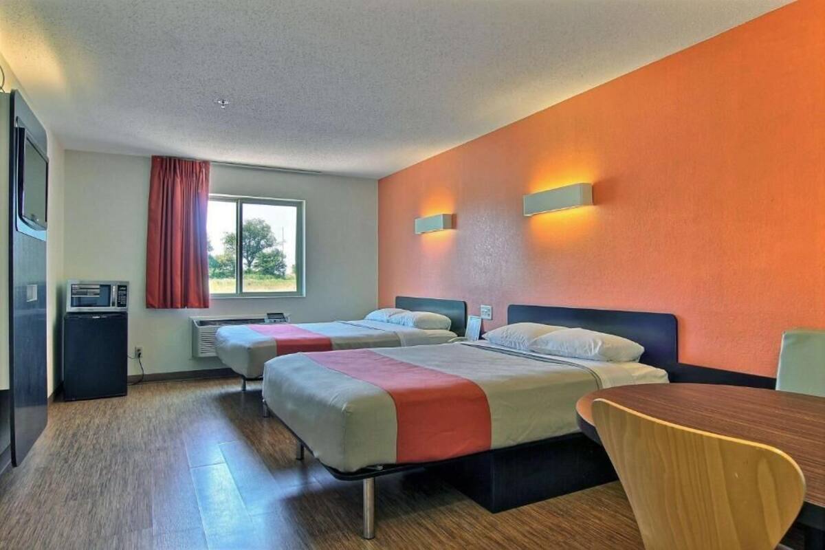 Une chambre d’hôtel avec deux lits, une table à manger et un four à micro-ondes.