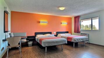 Ein Hotelzimmer mit zwei Betten, einem Schreibtisch, einem Stuhl und einem Fenster mit Vorhängen.