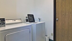 A laundry room with a front-loading washer and dryer, a control panel, and a door.