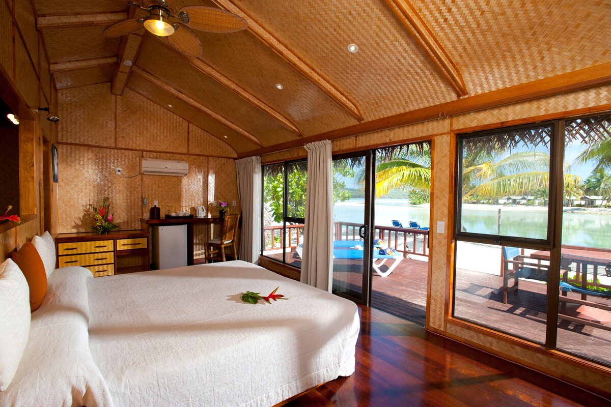 Un dormitorio amplio con una cama grande, un escritorio y vistas a una piscina y palmeras.