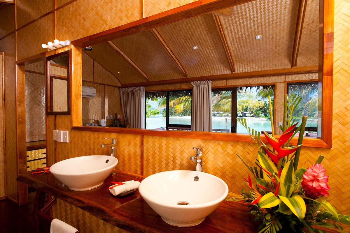Un baño con dos lavamanos, un espejo grande y vista a una piscina.