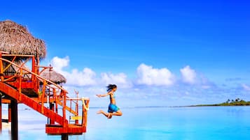Escape to a serene tropical paradise with access to calm turquoise waters and a staircase leading down to the water's edge.