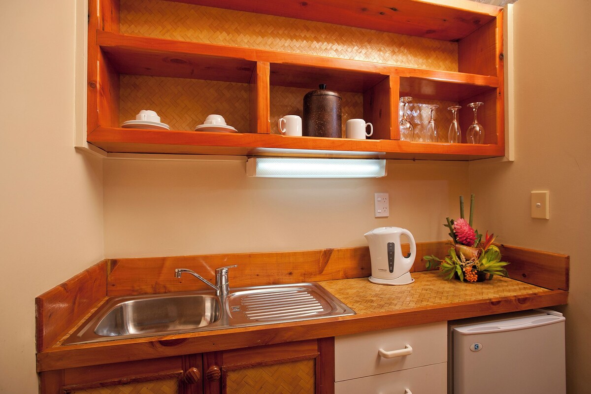 Una cocina con encimera de madera, un fregadero, una cafetera y un refrigerador pequeño.
