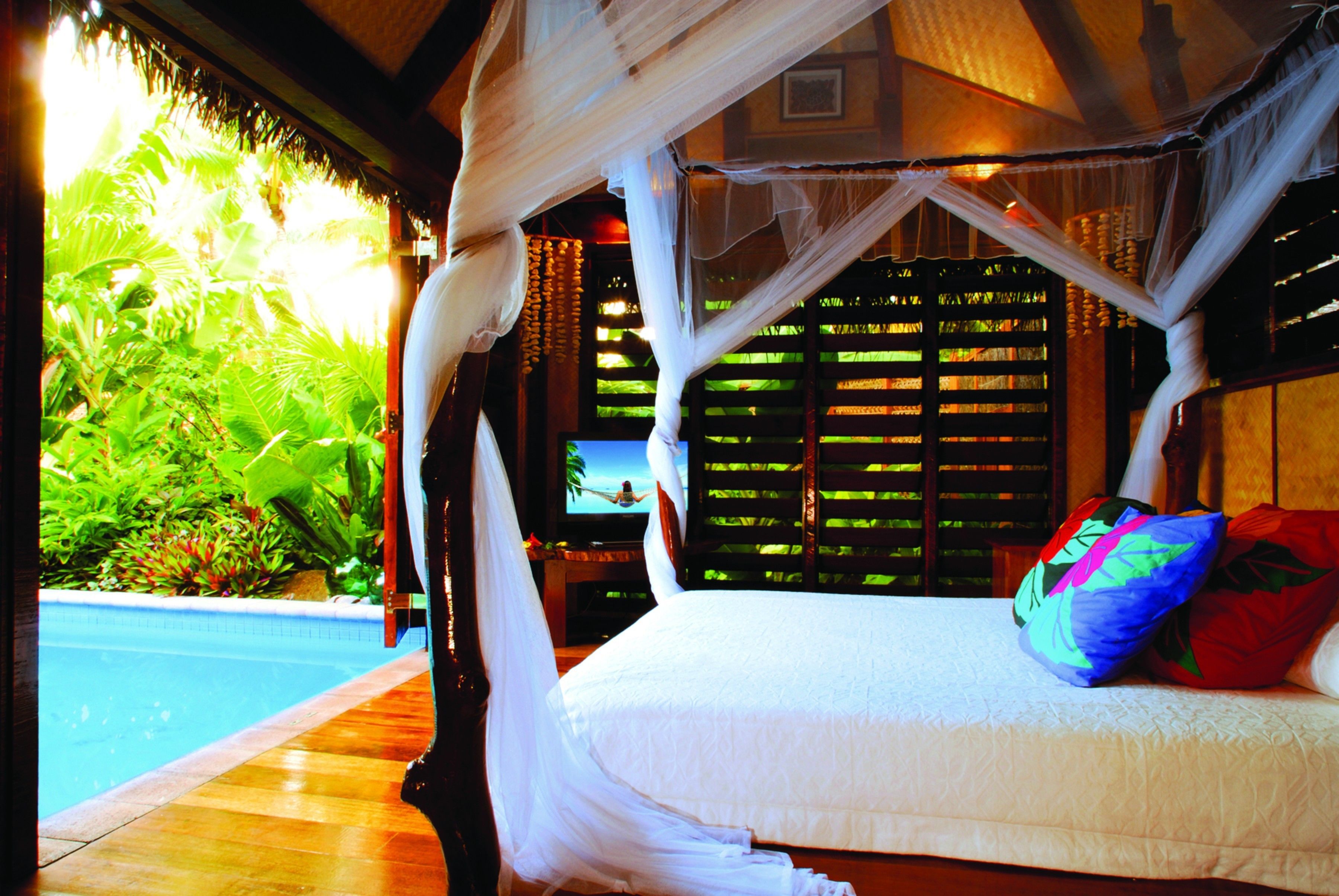 Ein Schlafzimmer mit Bett, Fernseher und Blick auf einen Pool.