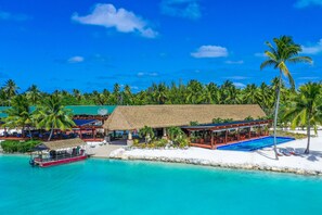A resort with a pool, beach, and thatched-roof structures. - Aitutaki Lagoon Private Island Resort - Adults Only (Aitutaki)