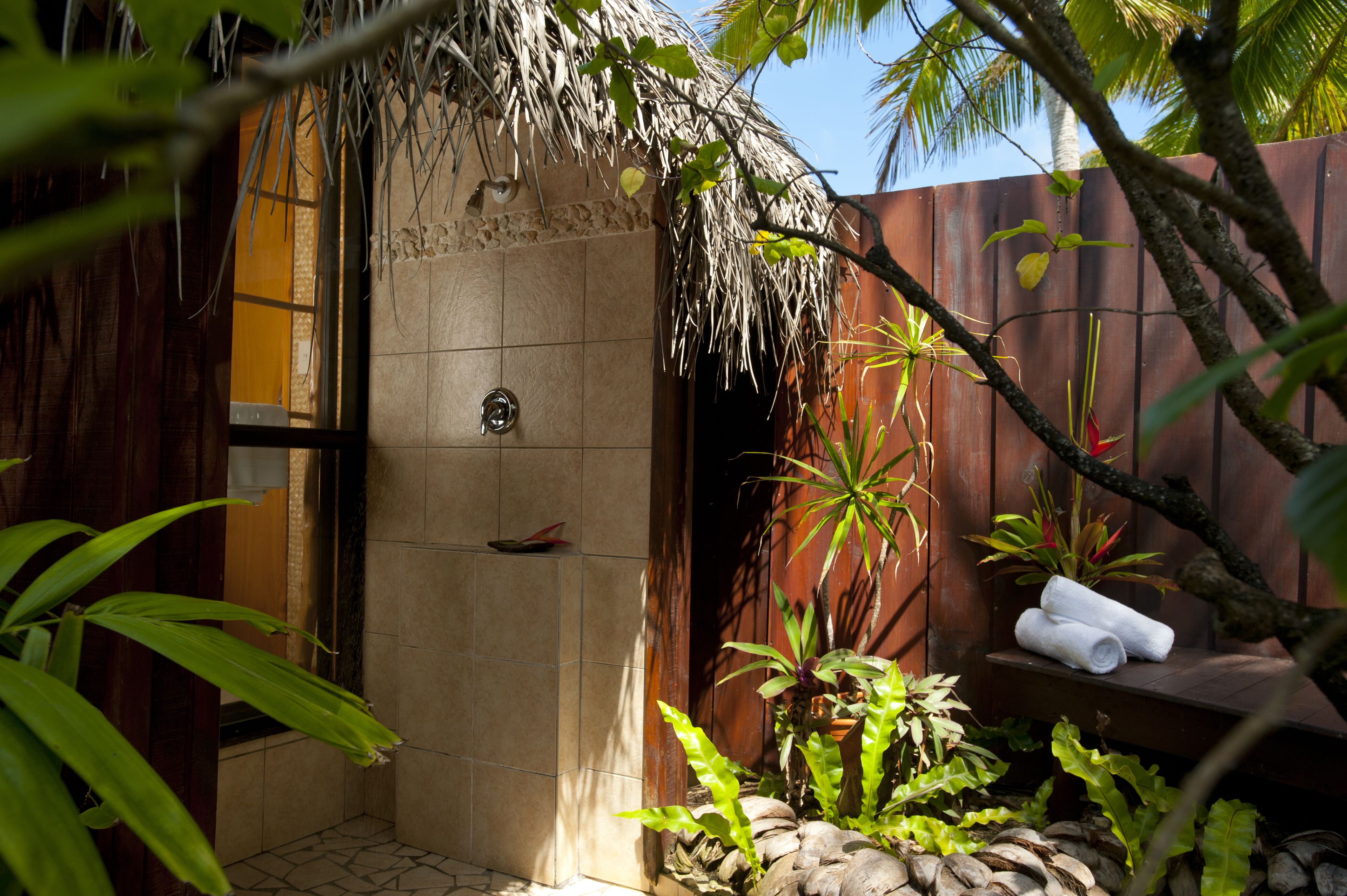 A shower area with a tiled wall, a door, and a shelf with towels.