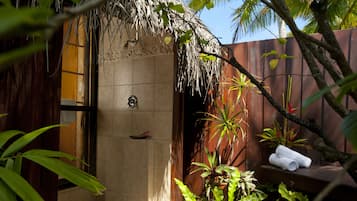 A shower area with a tiled wall, a door, and a shelf with towels.