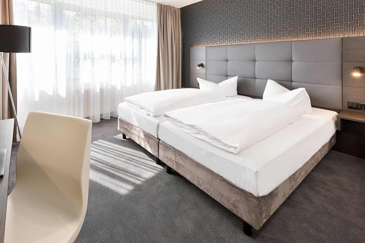 Habitación de hotel con una cama doble, un escritorio con una computadora portátil, una silla y una lámpara.
