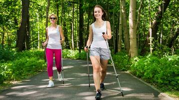 Two people walking on a paved path surrounded by greenery.