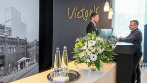 Un comptoir d’accueil agrémenté d’un grand arrangement floral, de deux bouteilles d’eau et d’un plateau avec des verres.