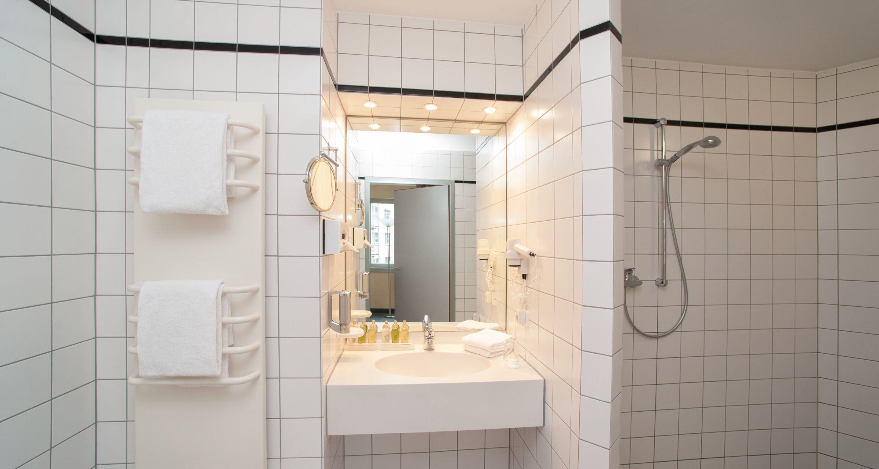 A modern bathroom with a white sink, mirror, and shower.