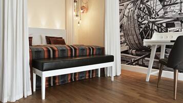 A compact bedroom with a bed, bench, and a small table with a chair.