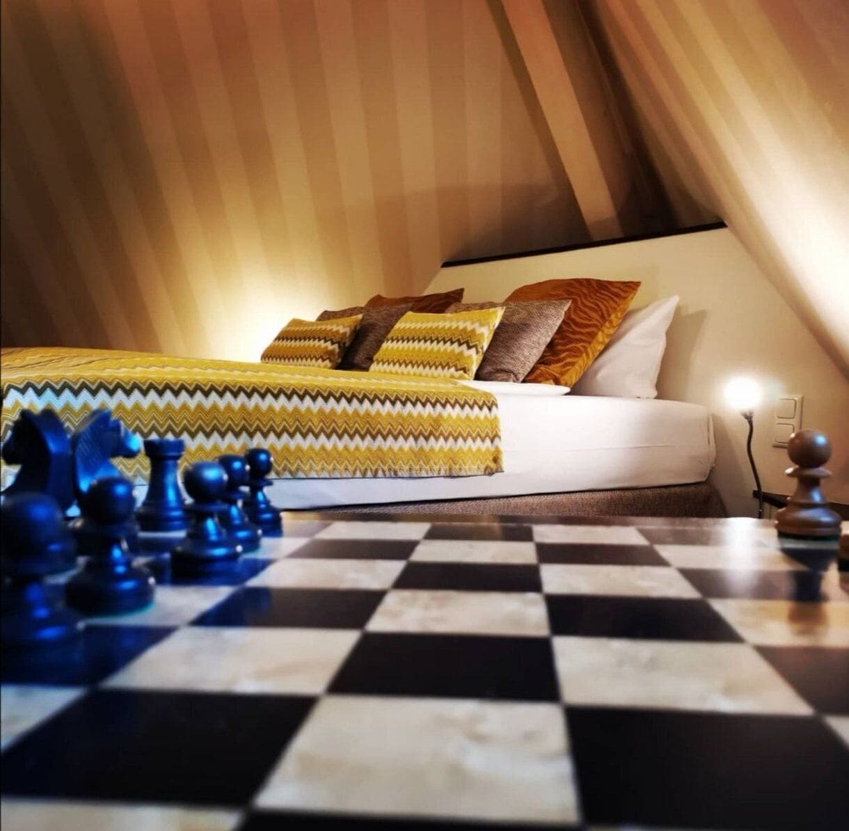 A bedroom with a bed, pillows, and a chessboard.