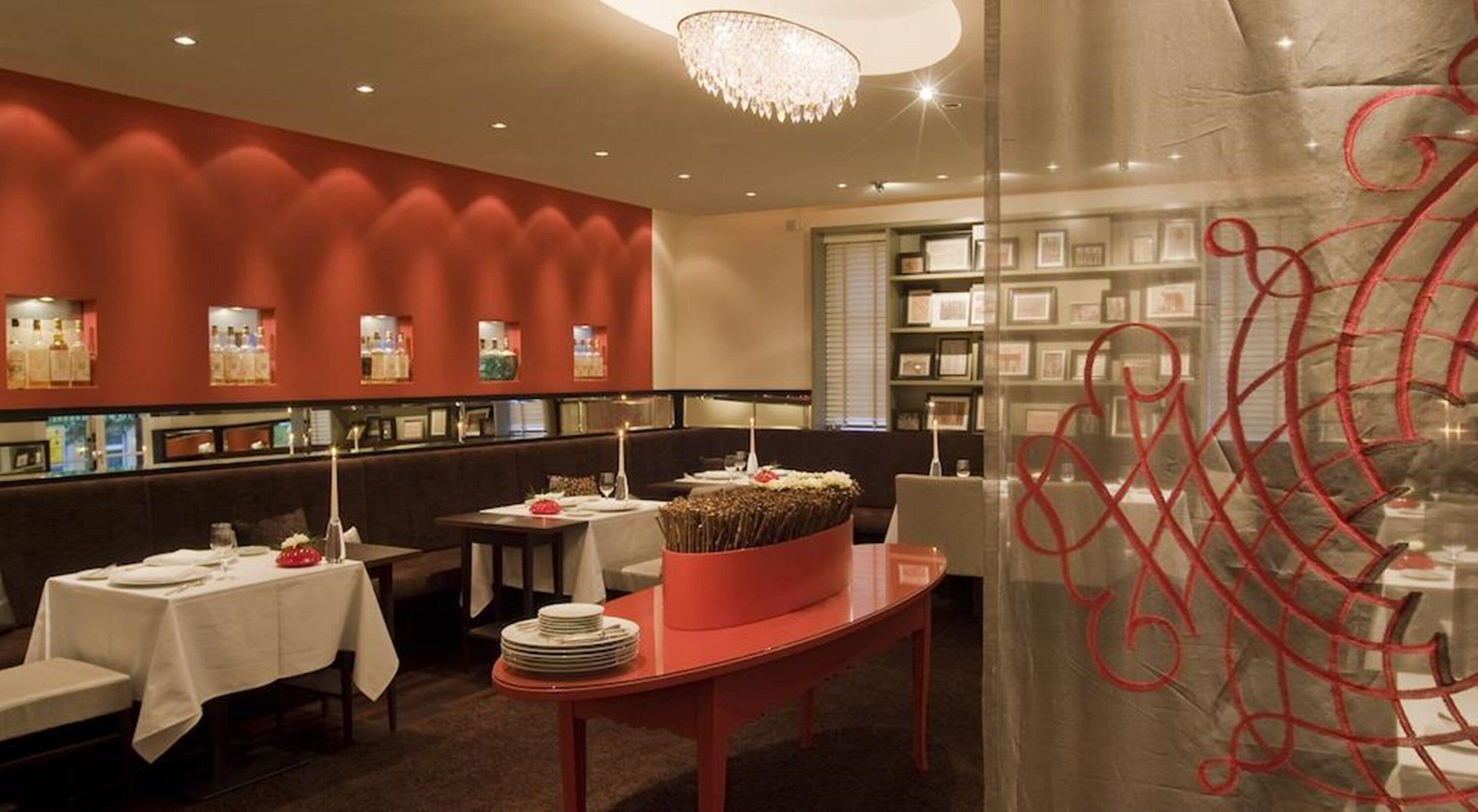 A restaurant with booths, tables, and a red accent wall.