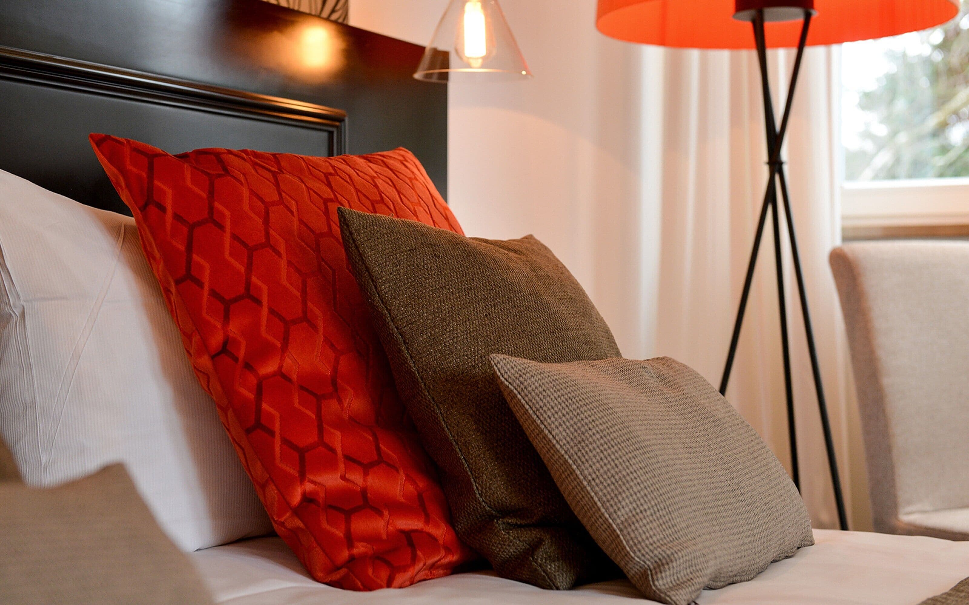 A bed with two pillows, a floor lamp, and a window.