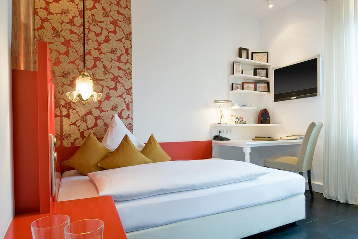 Una habitación de hotel con cama, mesita de noche y escritorio con silla.