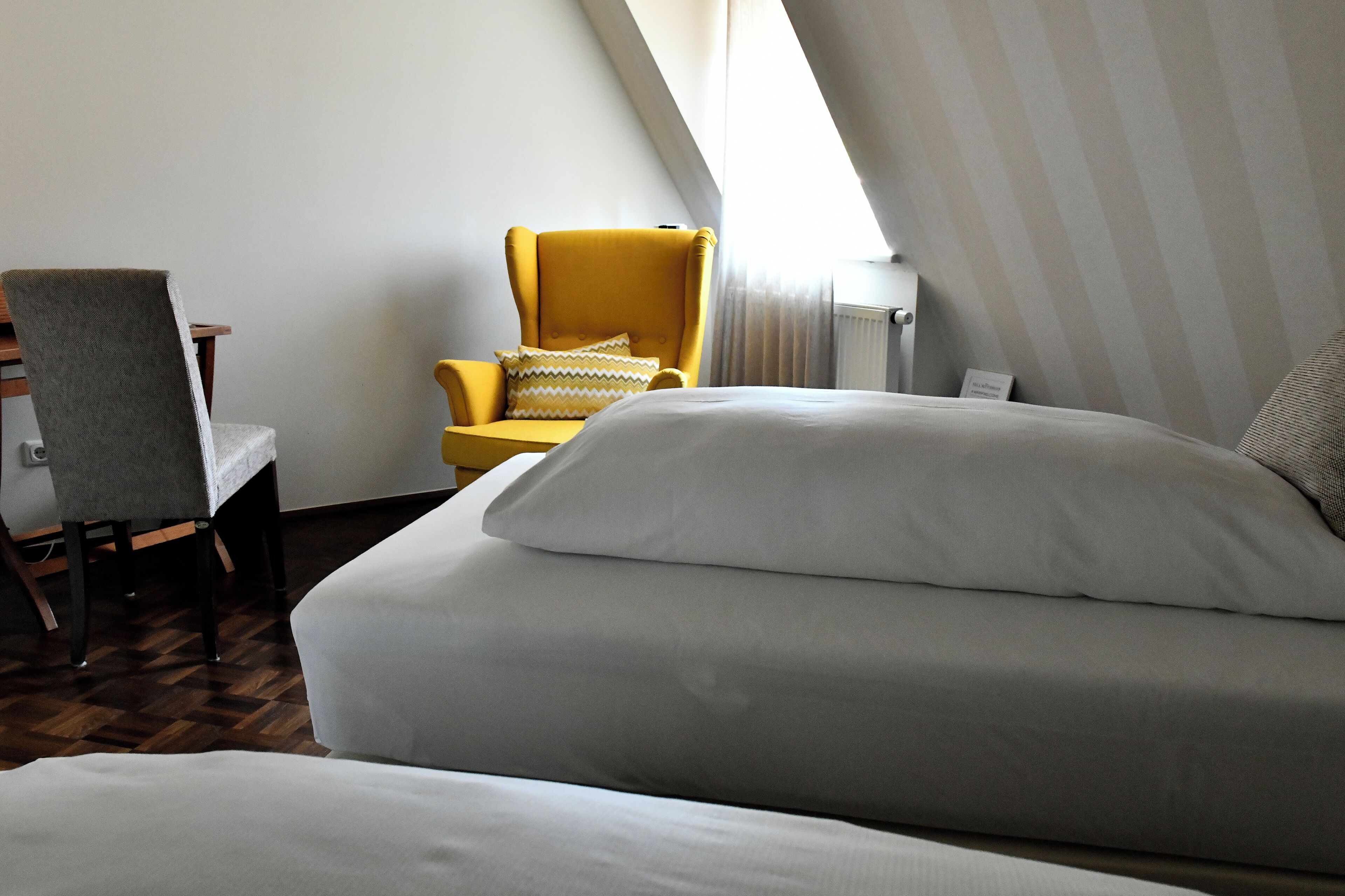 Habitación de hotel con cama, una silla y ventana.