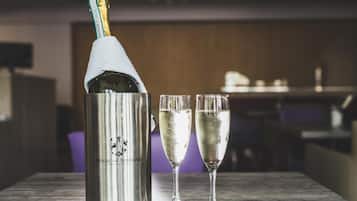 A bottle of champagne with two glasses on a wooden table.