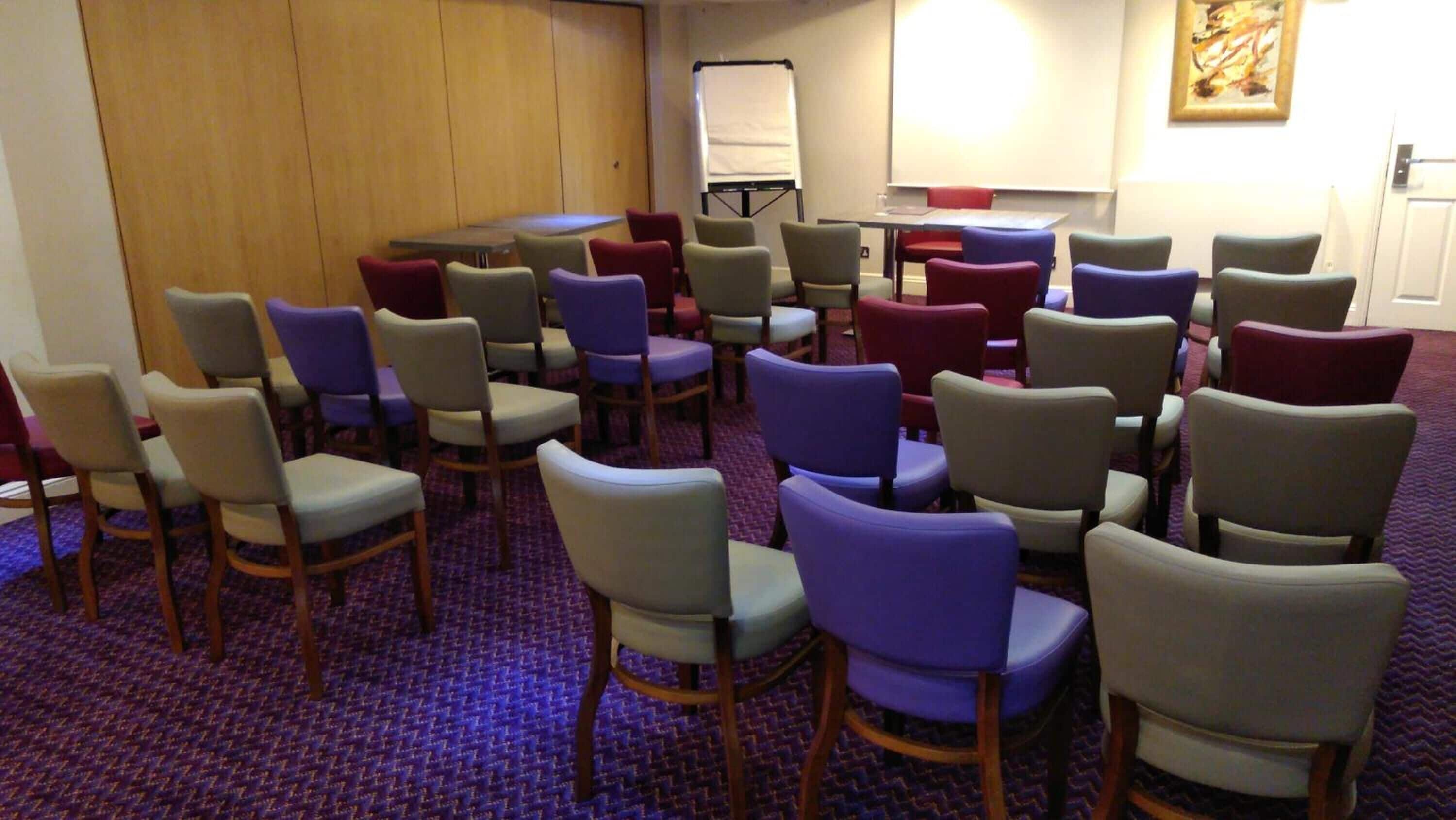 Una sala de conferències amb files de cadires, una pissarra i una pantalla de projector.