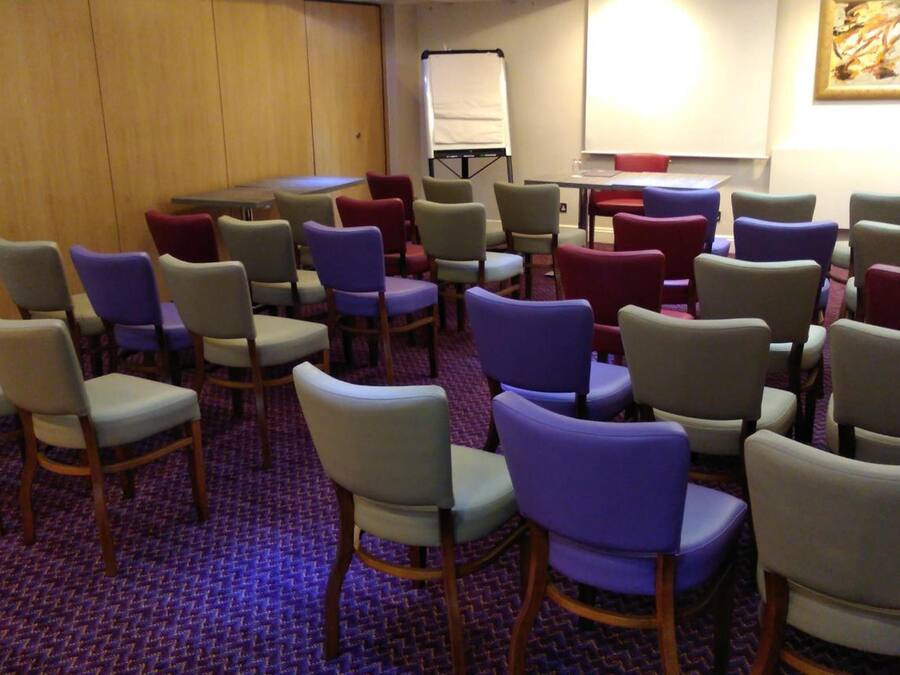 A conference room with rows of chairs, a whiteboard, and a projector screen.