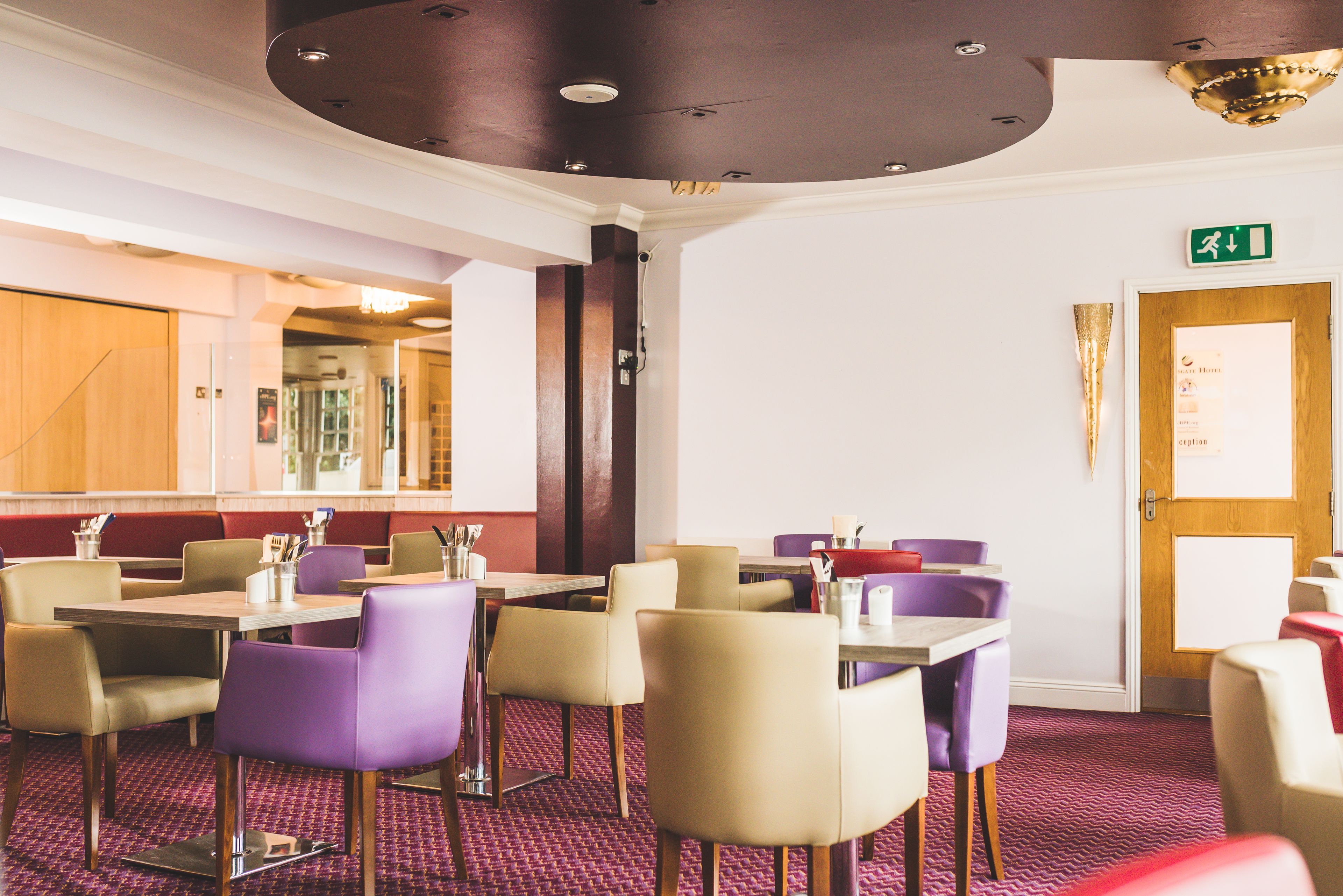 A restaurant with booths and tables, a wooden ceiling, and a red carpeted floor.