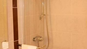 Un baño moderno con ducha de vidrio, lavamanos blanco y encimera oscura.