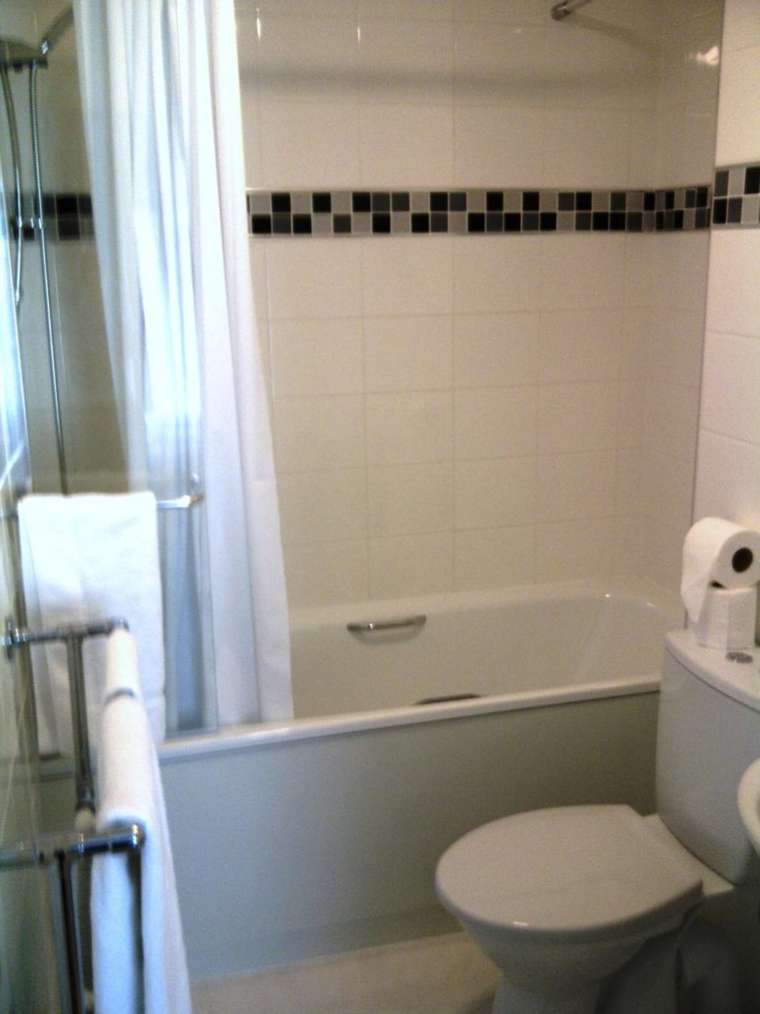 Un baño con bañera, inodoro y mampara de cristal.