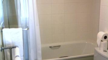 A bathroom with a bathtub, toilet, and a glass shower enclosure.