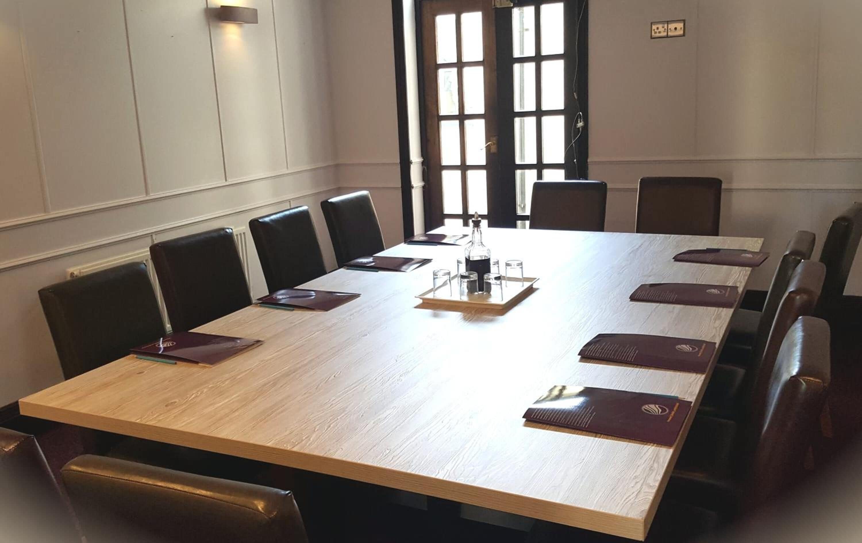 Un salón de conferencias con una mesa larga, sillas y una botella de agua.